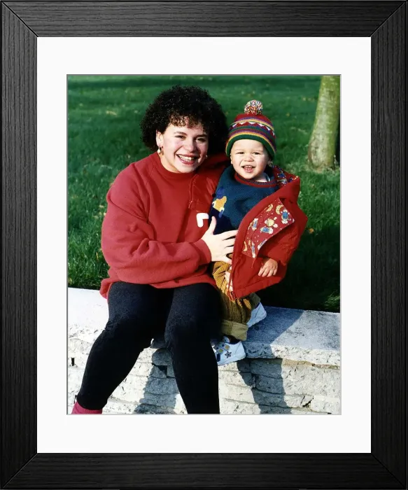 Framed Print : Cheryl Maker Actress who appears in TV soap Brookside sitting on wall with her son