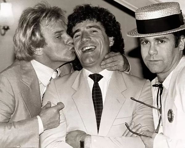 Comedian Freddie Starr kisses England striker Kevin Keegan as Pop star Elton John looks