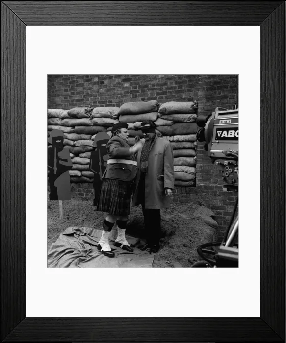Framed Print : A scene from The Avengers tv programme Patrick Macnee being blind folded by Roy Kinner Framed Print : A scene from The Avengers tv programme Patrick Macnee being blind folded by Roy Kinner