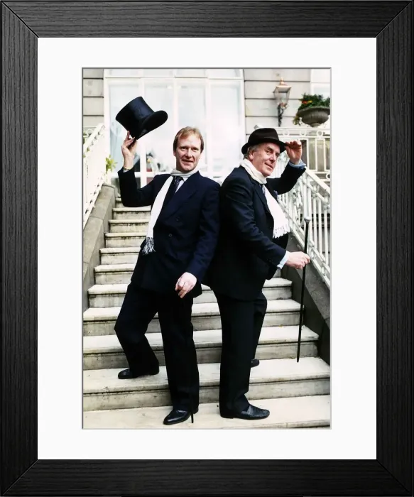 Framed Print : George Cole actor and Dennis Waterman standing on doorsteps raising a top hat and cane Framed Print : George Cole actor and Dennis Waterman standing on doorsteps raising a top hat and cane