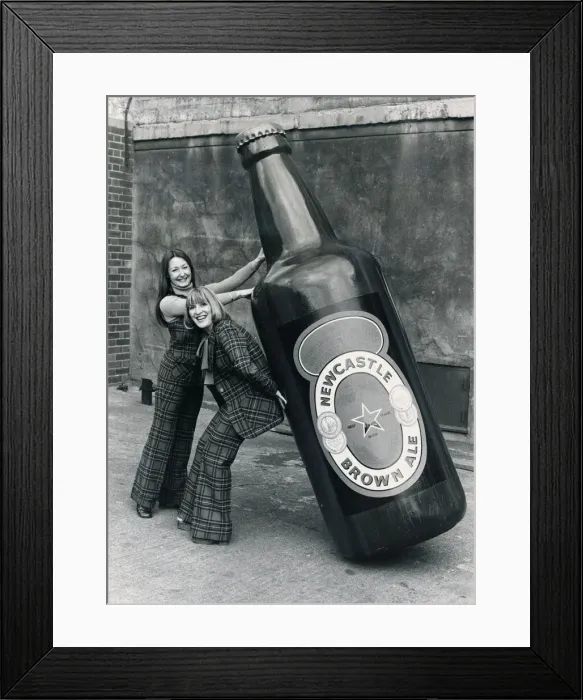 Framed Print : Brenda Kelly (without jacket) and Jennifer Donkin holding a nine foot tall bottle of Framed Print : Brenda Kelly (without jacket) and Jennifer Donkin holding a nine foot tall bottle of