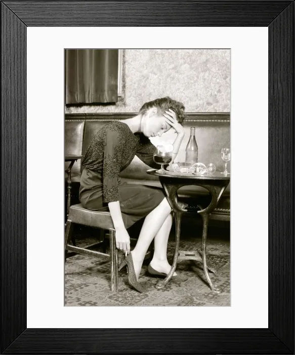 Framed Print : A women who has had to much to drink holds her head (posed by model) Framed Print : A women who has had to much to drink holds her head (posed by model)