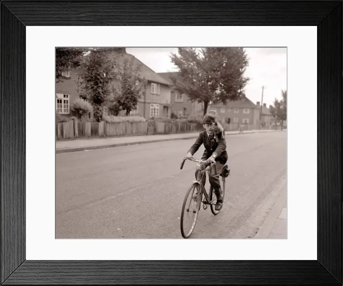 Framed Print : A young schoolboy comes home from school on his bicycle Framed Print : A young schoolboy comes home from school on his bicycle