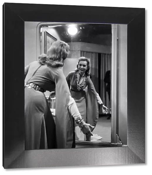 Actress Janet Leigh looks at her reflection in the mirror at a costume fitting for