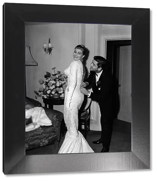 Actress Anita Ekberg has her dress zipped up by her husband Anthony Steel