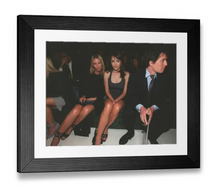 Framed Print : Hugh Grant actor with girlfriend Liz Hurley sits on bench to watch the Versace fashion