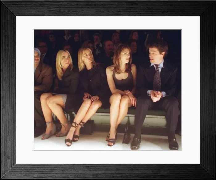 Framed Print : Hugh Grant actor with girlfriend Liz Hurley sits on bench to watch the Versace fashion
