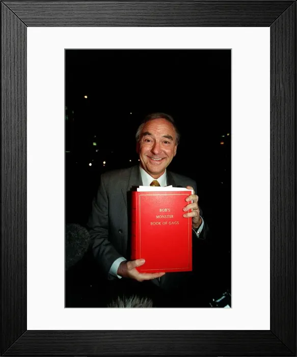 Framed Print : Bob Monkhouse Comedian and TV Presenter holding the book of gags that was stolen from his Framed Print : Bob Monkhouse Comedian and TV Presenter holding the book of gags that was stolen from his