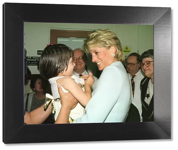 Diana, Princess of Wales, smiles as she holds a young girl at Cook County Hospital