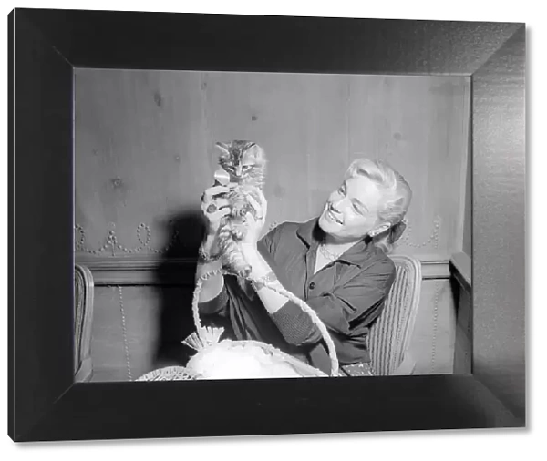 Actress Simone Signoret holding a tiny kitten at a press conference
