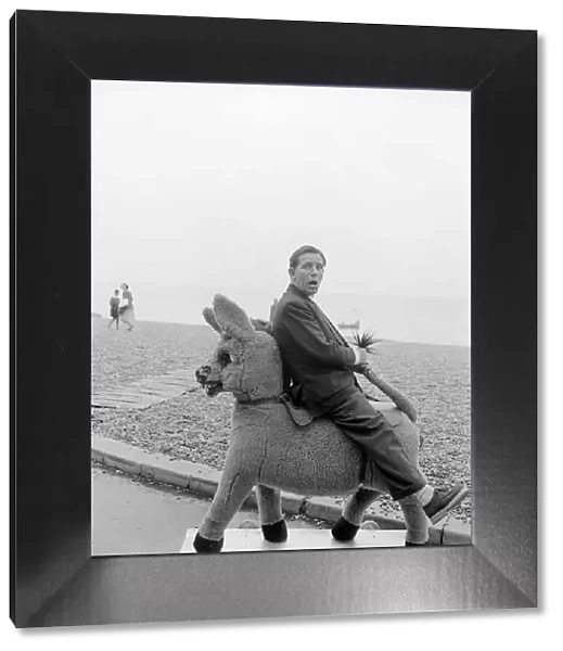 Comedian and actor Norman Wisdom photographed on Brighton Beach on a stuffed donkey