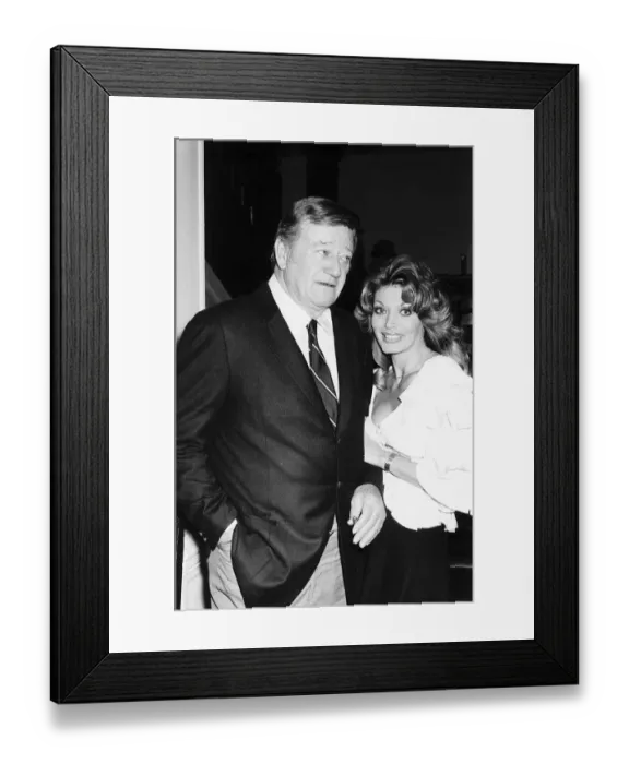 Framed Print : John Wayne with Miss Toni Holt who asked him to do a nude pin-up for her magazine