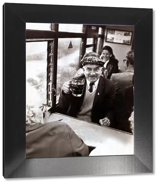 An elderley man enjoying a pint of beer on a Ffestiniog Railway train in North Wales