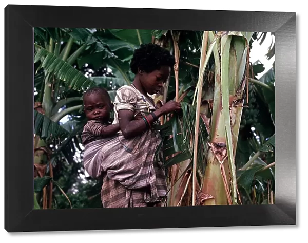 A young African girl strips a Banana Leaf to make a skirt in Quimbango