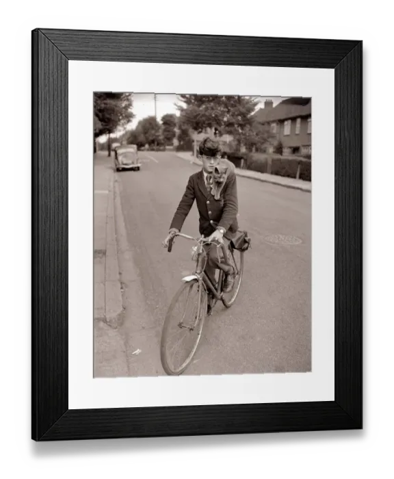 Framed Print : A young schoolboy comes home from school on his bicycle Framed Print : A young schoolboy comes home from school on his bicycle