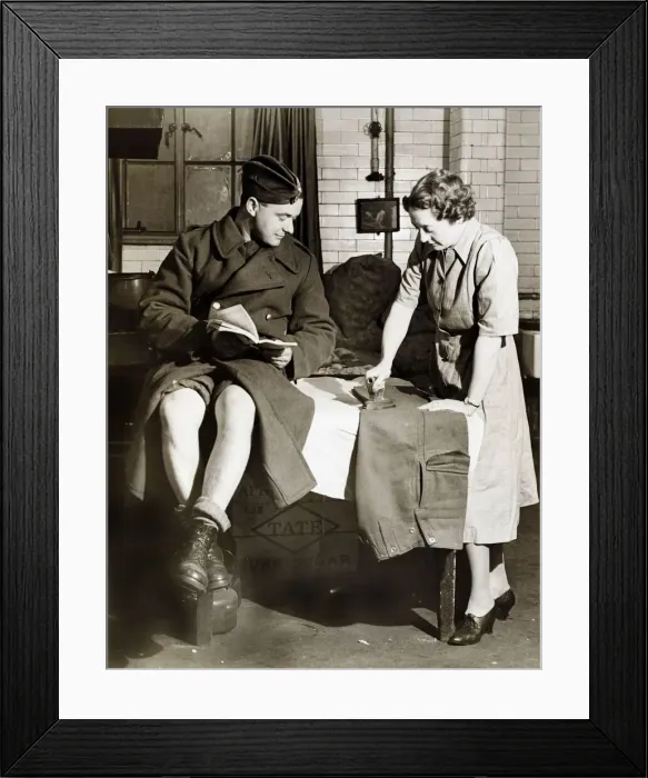 Framed Print : Soldier sits and waits as his trousers are pressed - March 1942 Framed Print : Soldier sits and waits as his trousers are pressed - March 1942