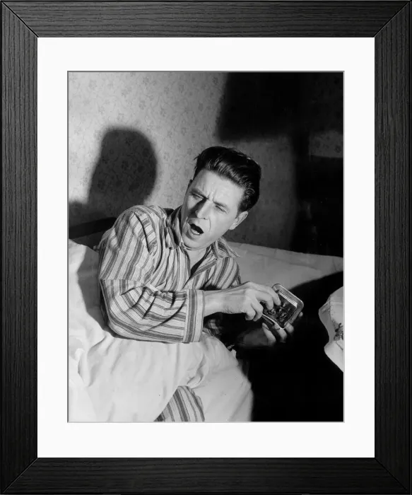 Framed Print : Sleepy Man. A man wakes up, yawning, turns off his alarm clock Framed Print : Sleepy Man. A man wakes up, yawning, turns off his alarm clock