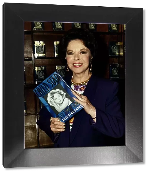 Shirley Temple actress holding up a copy of her book Child Star May 1989