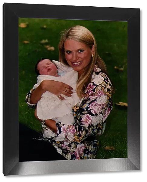 Anneka Rice holding baby smiling sitting on grass wearing flowery print shirt TV
