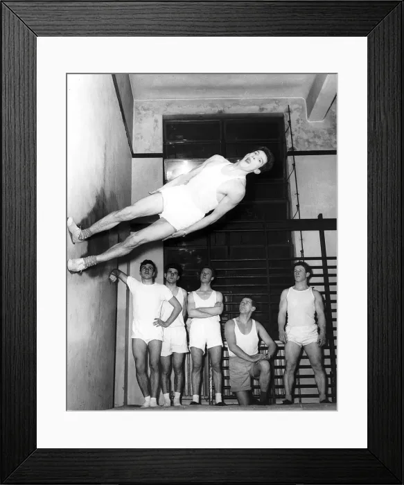 Framed Print : Gymnast Ken Popplewell walking on a wall watched by other members of the Ilford gymnastic