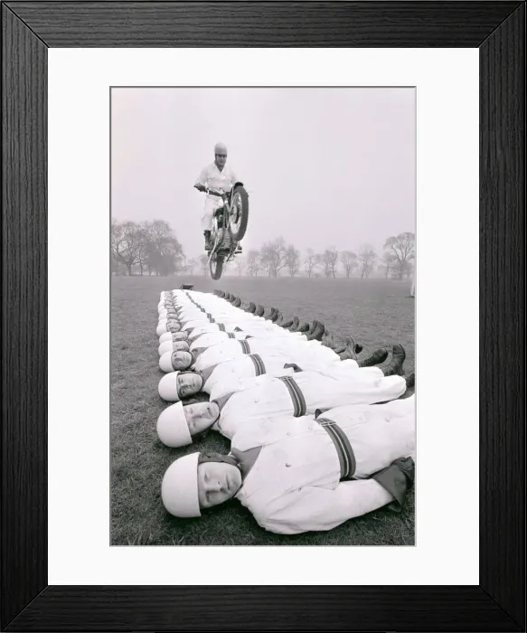 Framed Print : Stunt team in action 1966 Man leaps on a motorcycle over men lying on the ground