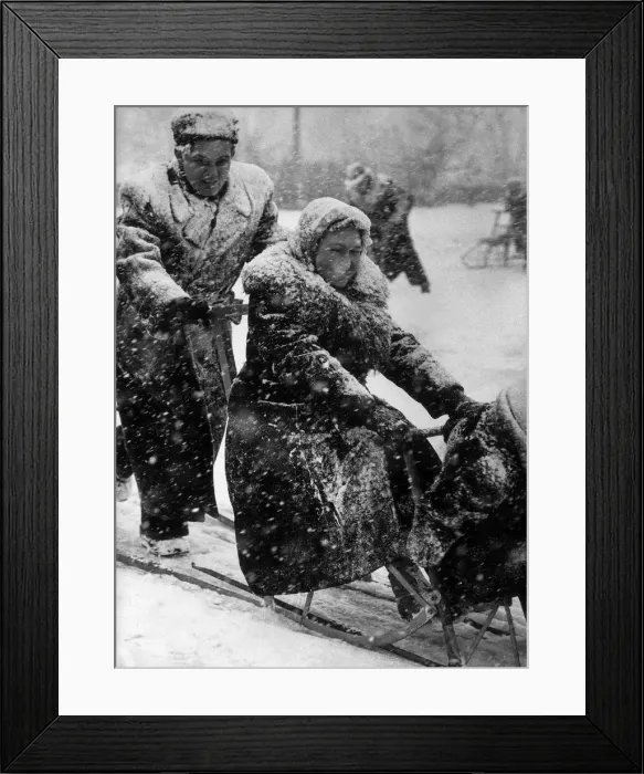 Framed Print : A young Russian couple playing in the snow in Moscow, the young man pushes the sleigh Framed Print : A young Russian couple playing in the snow in Moscow, the young man pushes the sleigh