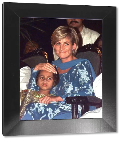 Diana, Princess of Wales, sits with a young girl at a fund raising event at the Shaukat