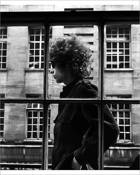 American singer Bob Dylan pictured walking past a shop window during his visit to London