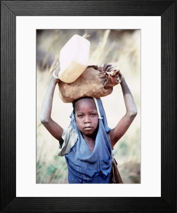: Mali Dogon Tribe a young girl carrying heavy item on her head : Mali Dogon Tribe a young girl carrying heavy item on her head