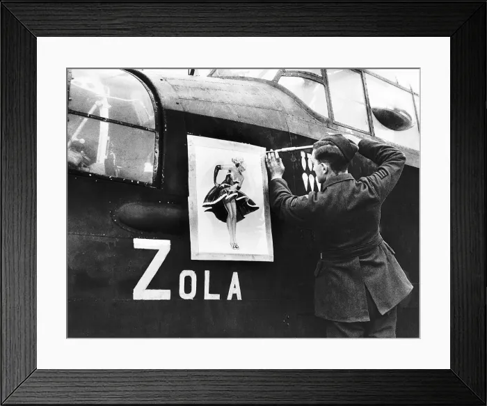 Framed Print : A Lancaster bomber crewman screws on a nose art painting of Zola on to the side of