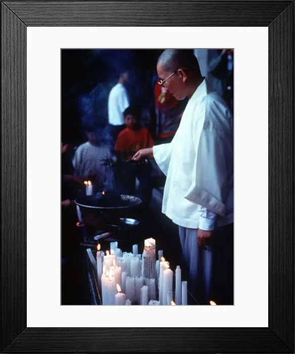  : Buddhist monk lighting candles at a Buddhist church service circa 1997