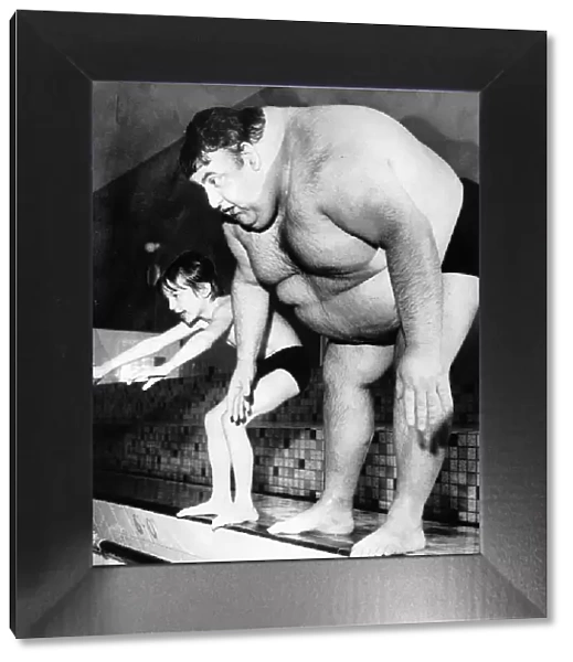 Obese fat man tries to dive into swimming pool next to small boy. Circa 1980