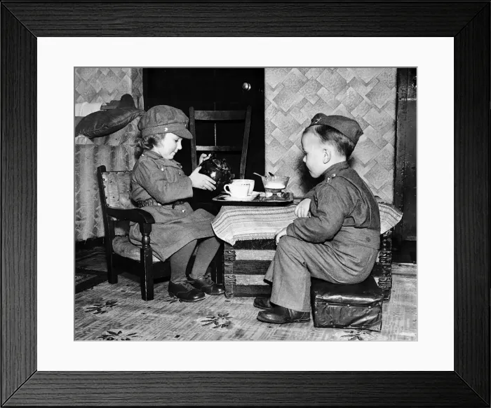 Framed Print : Children playing games at home dressed in army uniform and pouring tea during WW2 Framed Print : Children playing games at home dressed in army uniform and pouring tea during WW2