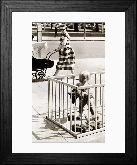 Framed Print : Toddler in a play pen, placed on a pavement. Circa 1960 Framed Print : Toddler in a play pen, placed on a pavement. Circa 1960