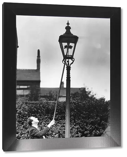 A lamplight at work, holding ignition rod to gas jet in lamp. Circa 1930