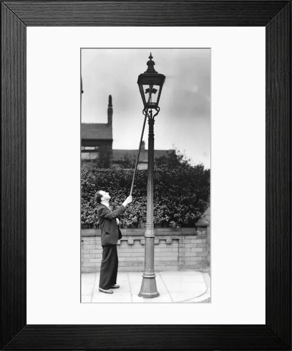 Framed Print : A lamplight at work, holding ignition rod to gas jet in lamp. Circa 1930 Framed Print : A lamplight at work, holding ignition rod to gas jet in lamp. Circa 1930
