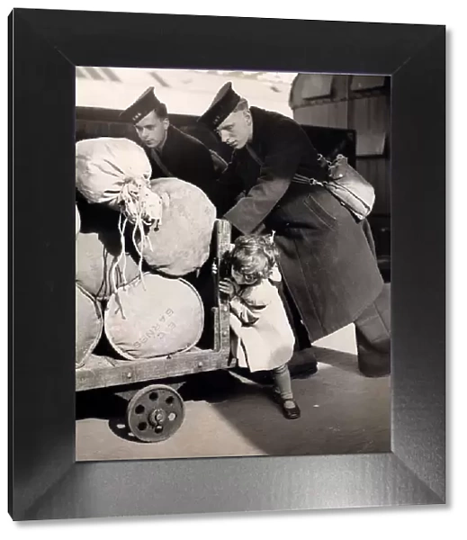 Little Jean Butcher age 3 gives two sailors a hand to push the barrow containing their
