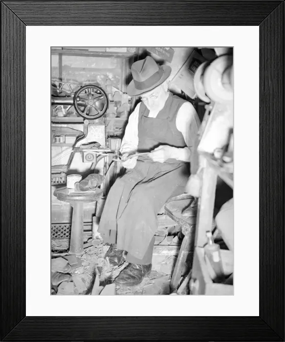 Framed Print : A cobbler working in his workshop. circa 1930