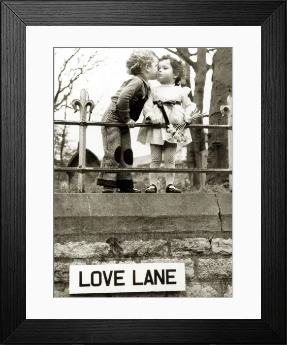 Framed Print : Two kids kissing next to Love Lane street sign. Circa 1950