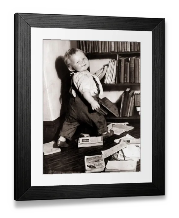 Framed Print : It looks like this little boy would love to become a librarian! Circa 1950