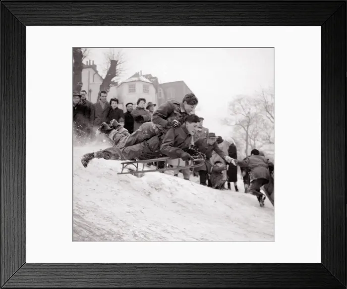 Framed Print : Boys goes flying down a snow covered hill on a sledge at Hampstead Heath February