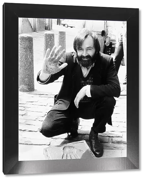 Bill Forsyth film producer making hand impression hand print in paving stone outside