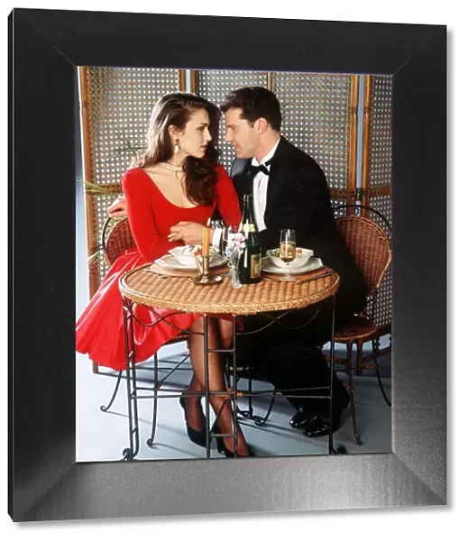 Couple having dinner staring into each others eyes drinking champagne