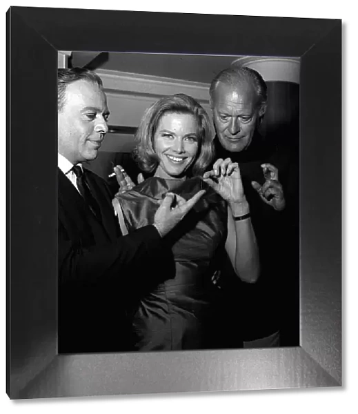 Actors Herbert Lom, Honor Blackman and Curt Jurgens holding thread of cotton which in
