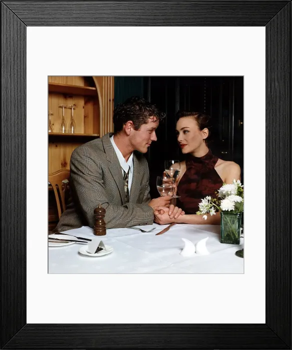 Framed Print : Young man and woman holding hands at dinner table looking into each others eyes Framed Print : Young man and woman holding hands at dinner table looking into each others eyes