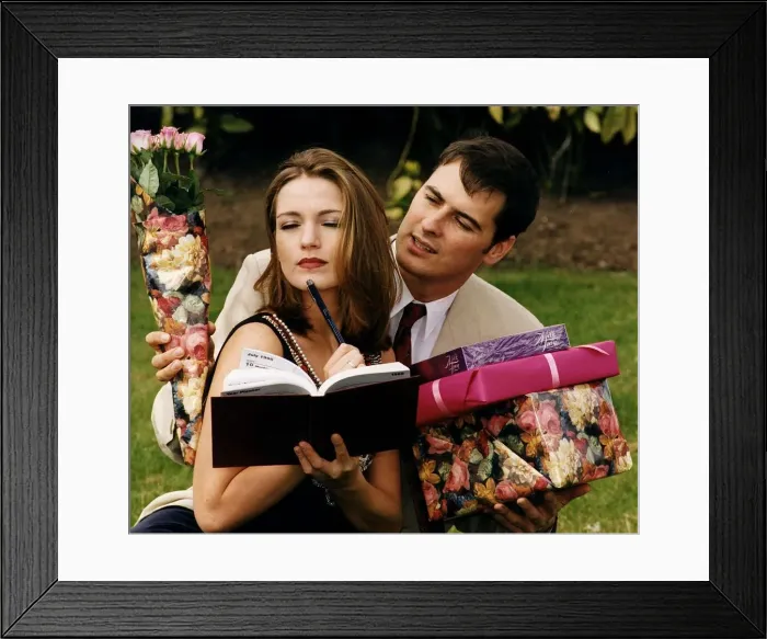 Framed Print : Girl writing in her diary while boyfriend tries to give her presents chocolates Framed Print : Girl writing in her diary while boyfriend tries to give her presents chocolates