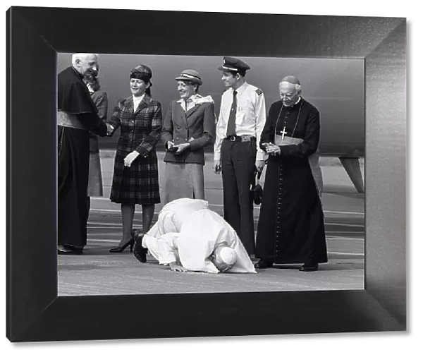 Pope John Paul II kneels down and kisses the ground at Cardiff airport on his visit to
