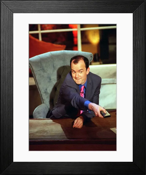 Framed Print : Jack Docherty sitting in chair left hand on desk right hand pressing television remote Framed Print : Jack Docherty sitting in chair left hand on desk right hand pressing television remote
