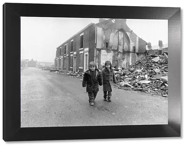 Two boys walk pass the partially demolished row of terrace houses in Blackburn May