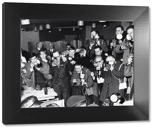 A room full of photographers take pictures of pop group The Beatles during their visit to
